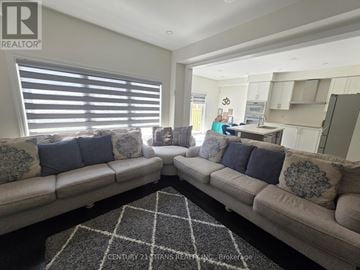 Oshawa (Eastdale) apartment for rent - A living room with a large couch and a rug in front of it.