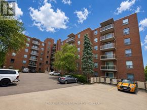 St. Catharines (Downtown) multi-family for rent - A parking lot with cars and a building in the background.