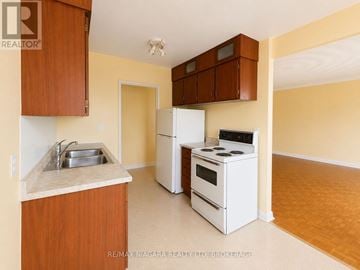 St. Catharines (Downtown) multi-family for rent - A kitchen with white appliances and wooden cabinets.