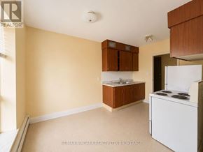 St. Catharines (Downtown) multi-family for rent - A kitchen area with a white fridge and brown cabinets.