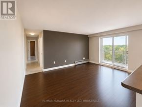 St. Catharines (Downtown) multi-family for rent - A spacious room with wooden flooring and a large window overlooking the outdoors.