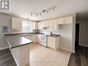 St. Catharines (E. Chester) multi-family for rent - A kitchen with white appliances and cabinets.