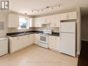 St. Catharines (E. Chester) multi-family for rent - A kitchen with white appliances and cabinets.