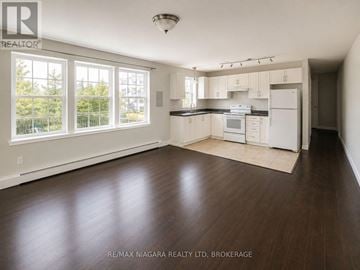 St. Catharines (E. Chester) multi-family for rent - A well lit kitchen with white appliances and wooden floors.