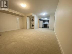 Coquitlam apartment for rent - A spacious room with a washer and dryer in it.