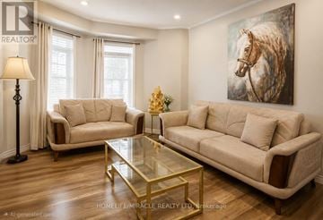 Brampton (Fletcher's Meadow) townhouse for rent - A living room with a beige couch, a glass coffee table, and a painting of a horse on the wall.