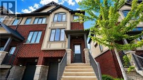 Ancaster townhouse for rent - A multi-story residential building with a red brick facade and a tree in front.