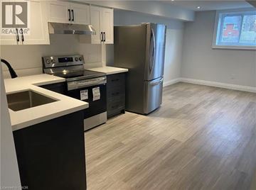 Kitchener apartment for rent - A kitchen with a stainless steel refrigerator, sink, and cabinets.