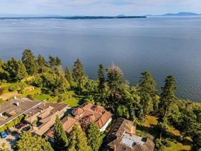 Surrey apartment for rent - A large house with a swimming pool is surrounded by trees and overlooks a body of water.