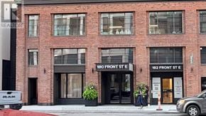 Toronto (Moss Park) condo for rent - A red brick building with a black awning and a sign that reads "182 Front St E".