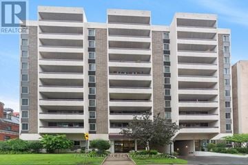Ottawa condo for rent - A large apartment building with a green lawn in front.