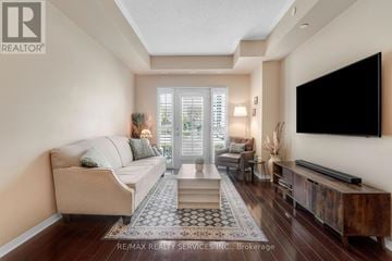 Mississauga (Churchill Meadows) condo for rent - A living room with a beige couch, a rug, and a flat screen TV mounted on the wall.