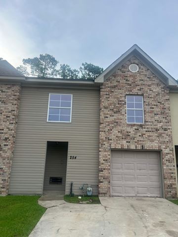Slidell apartment for rent - A house with a grey garage door and a brick wall.