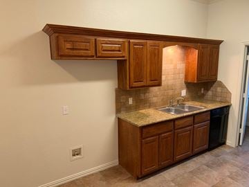 Temple triplex for rent - A kitchen with brown cabinets and a granite countertop.