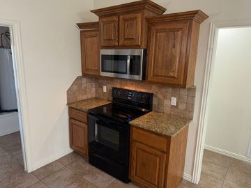 Temple triplex for rent - A kitchen with wooden cabinets and black appliances.