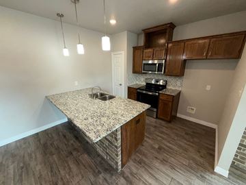Temple townhouse for rent - A kitchen with granite countertops and wooden cabinets.