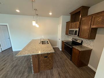 Temple townhouse for rent - A kitchen with wooden cabinets and a granite countertop.