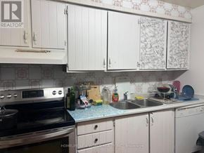 Toronto (Hillcrest Village) townhouse for rent - A kitchen with white cabinets and a black stove top oven.