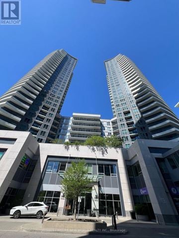 Markham (Thornhill) condo for rent - A modern building with a glass facade stands tall against a clear blue sky.