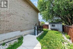 Milton (Be Beaty) apartment for rent - A brick wall with a black gate and a tree in the background.
