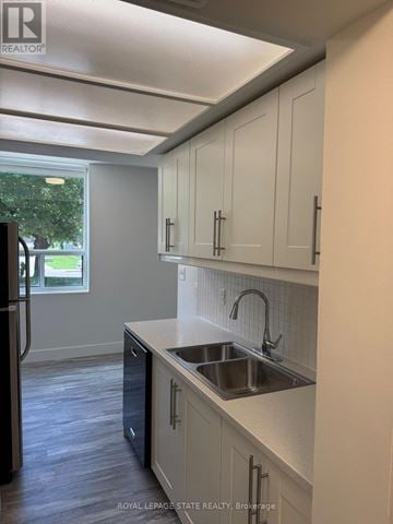 Hamilton (Durand) condo for rent - A kitchen with white cabinets and a black refrigerator.