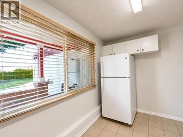 Richmond apartment for rent - A white refrigerator in a kitchen with a window covered in blinds.