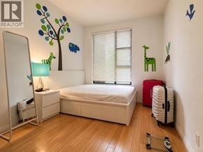 Vancouver townhouse for rent - A bedroom with a white bed, a red suitcase, and a wooden floor.