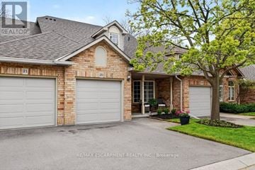 Burlington (Brant) townhouse for rent - A house with a garage and a tree in front.