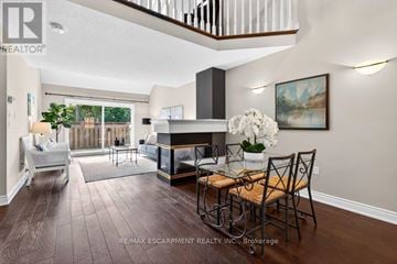 Burlington (Brant) townhouse for rent - A living room with a fireplace and a dining table set up.