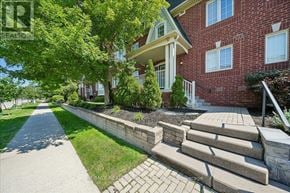 Mississauga (Cooksville) townhouse for rent - A red brick house with a white porch and a stone staircase leading to the front door.