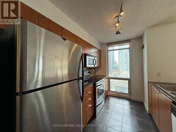 Toronto (Waterfront Communities) condo for rent - A kitchen with a stainless steel refrigerator and wooden cabinets.