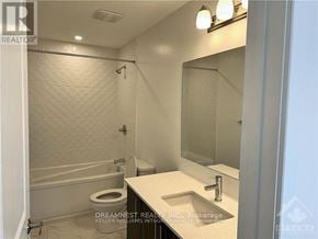 Ottawa townhouse for rent - A white bathroom with a toilet, sink, and shower.