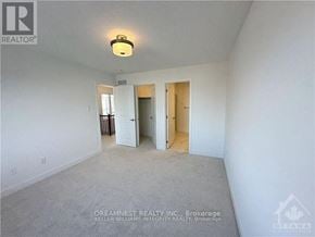 Ottawa townhouse for rent - A realtor photo of a white empty room with a carpet floor and a ceiling light.