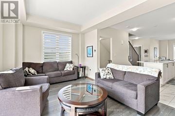 Thorold (Hurricane/Merrittville) townhouse for rent - A living room with a grey couch and a glass table.