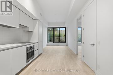 Toronto (Thorncliffe Park) condo for rent - A spacious kitchen with white cabinets and a view of trees through the window.
