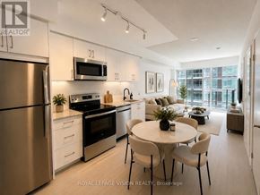 Toronto (Humber Heights) condo for rent - A modern kitchen with stainless steel appliances and a dining area with a round table and chairs.