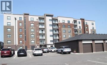Lakeshore condo for rent - A parking lot with cars and a building in the background.