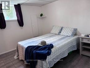 Welland (Lincoln/Crowland) fourplex for rent - A bedroom with a bed, a small table, and a window with curtains.