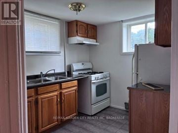 Welland (Lincoln/Crowland) fourplex for rent - A kitchen with wooden cabinets and a stove top oven.