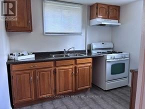 Welland (Lincoln/Crowland) fourplex for rent - A kitchen with wooden cabinets and a white stove top oven.