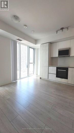 Toronto (Waterfront Communities) condo for rent - A spacious, well-lit kitchen with a wooden floor and white cabinetry.