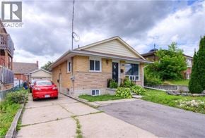 Kitchener apartment for rent - A red car is parked in front of a house with a realtor logo.