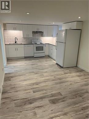 Kitchener apartment for rent - A kitchen with white appliances and wooden floors.