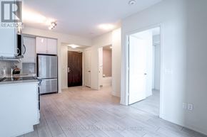 Toronto (Mimico) condo for rent - A kitchen with white cabinets and a refrigerator is shown in this image.