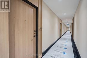 Toronto (Waterfront Communities) condo for rent - A long hallway with doors on either side and a sign on the floor.