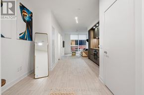 Toronto (Waterfront Communities) condo for rent - A long hallway with a white fridge on the left and a kitchen area on the right.