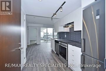 Toronto (Englemount-Lawrence) condo for rent - A modern kitchen with a stainless steel refrigerator and a view of the hallway outside.