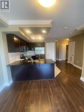 Woodstock (Woodstock - South) condo for rent - A modern kitchen with dark wood floors and a black countertop.