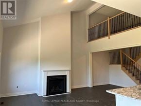 Uxbridge townhouse for rent - A spacious living room with a fireplace and a staircase.