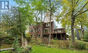 Mississauga (Clarkson) apartment for rent - A large brown house with a white door and windows is surrounded by trees.